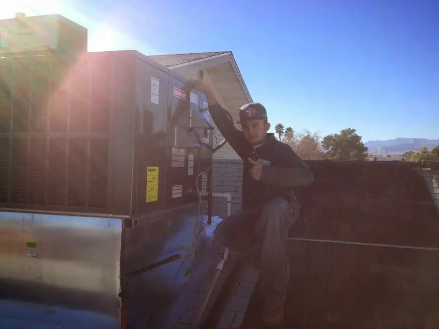 HVAC technician performing AC Tune-Up on a rooftop unit in Ludington
