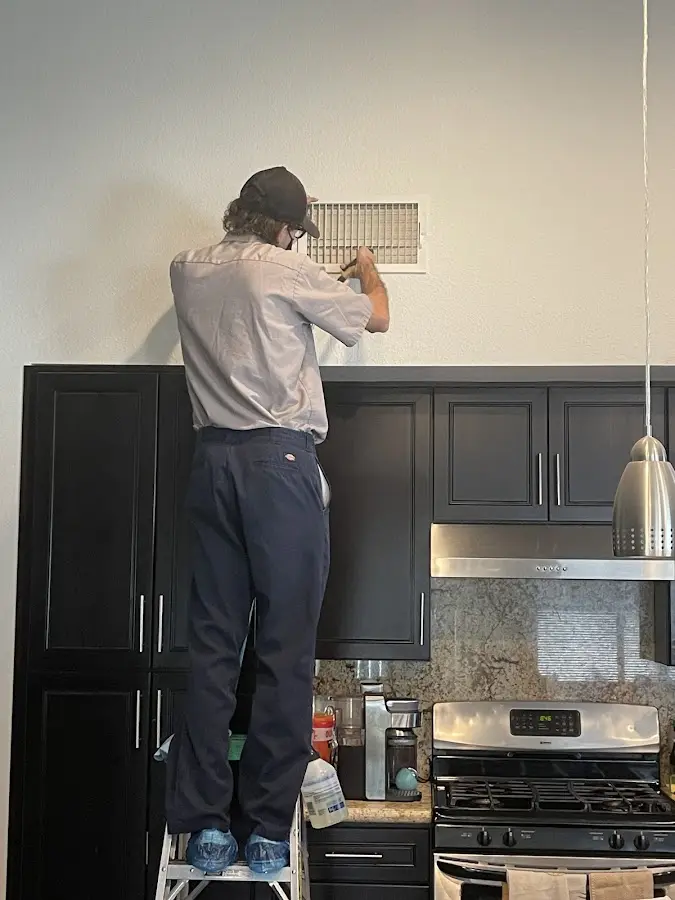 Technician inspecting an air vent during HVAC service in Ludington